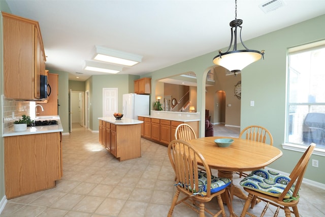 dining room featuring arched walkways, baseboards, visible vents, and a healthy amount of sunlight