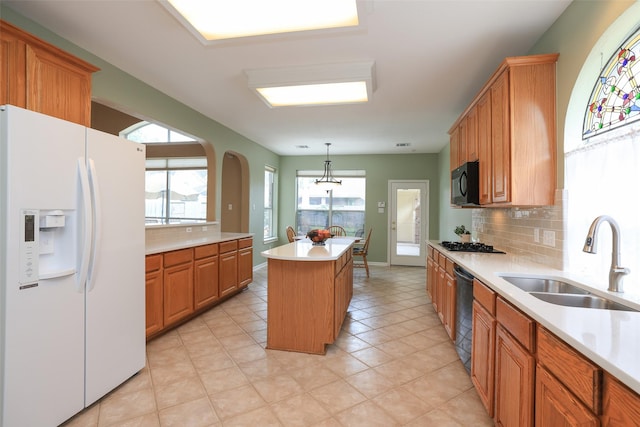 kitchen with a center island, light countertops, decorative backsplash, a sink, and black appliances