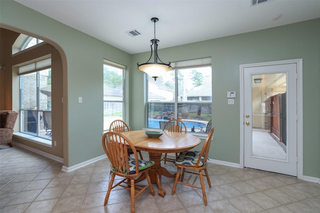 dining space with visible vents, arched walkways, baseboards, and light tile patterned flooring