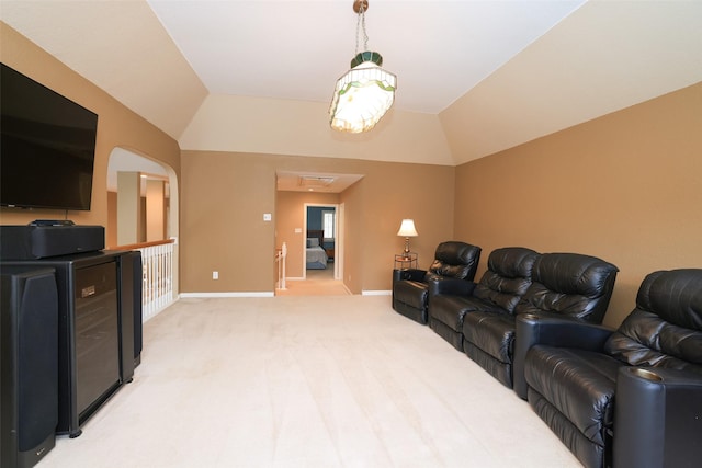 living area with light carpet, vaulted ceiling, and baseboards