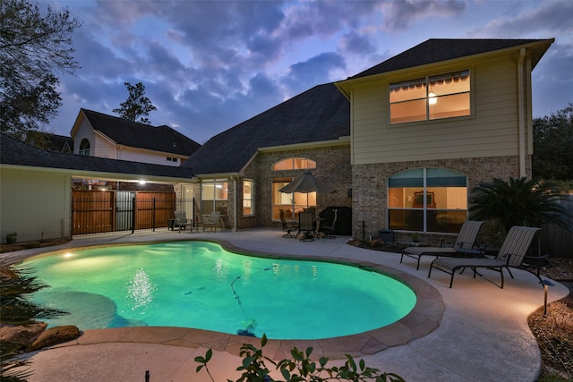 pool at dusk featuring a patio area, fence, and a fenced in pool