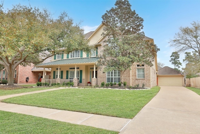 view of front facade with brick siding, covered porch, a standing seam roof, metal roof, and a front lawn