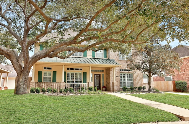 view of front of property with metal roof, a porch, brick siding, a standing seam roof, and a front yard