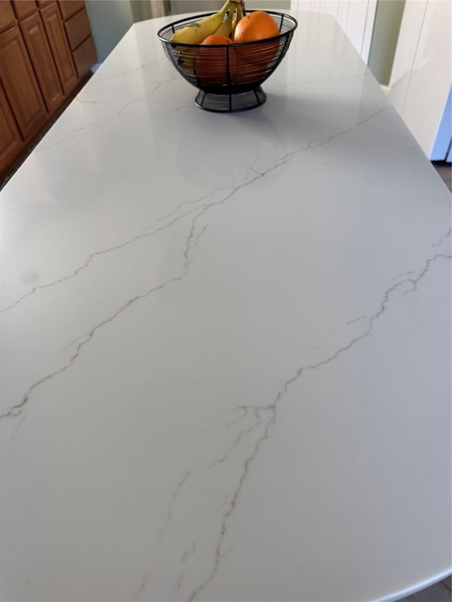 room details with light stone counters and brown cabinetry