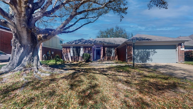 single story home with a front yard, brick siding, a garage, and driveway