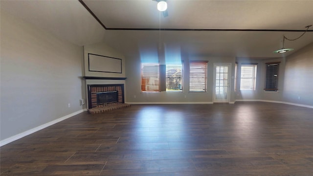 unfurnished living room with a brick fireplace, dark wood-style floors, and baseboards