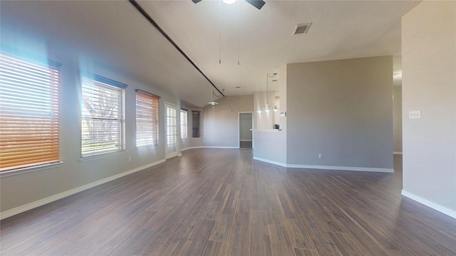 empty room featuring visible vents, a ceiling fan, baseboards, and dark wood-style flooring