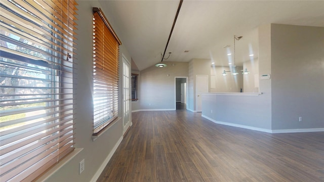 unfurnished living room with vaulted ceiling, wood finished floors, and baseboards