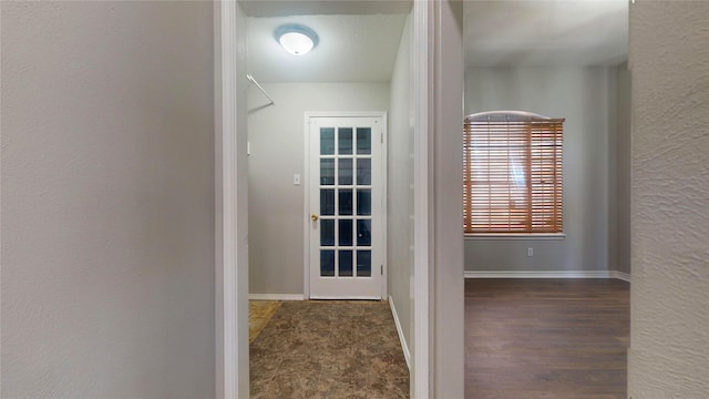 hallway featuring baseboards and a textured wall