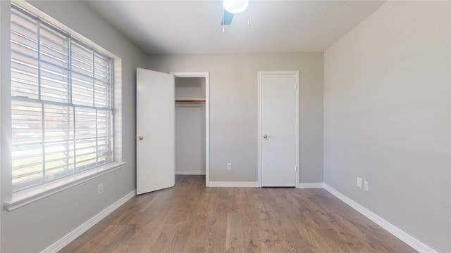 unfurnished bedroom with ceiling fan, a closet, baseboards, and wood finished floors