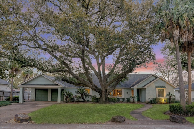 single story home featuring a lawn, fence, concrete driveway, an attached garage, and brick siding