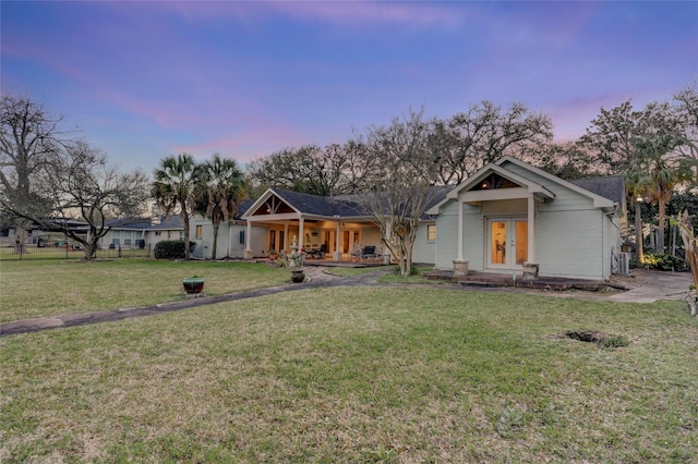 view of front of home with a front lawn, a porch, french doors, and brick siding