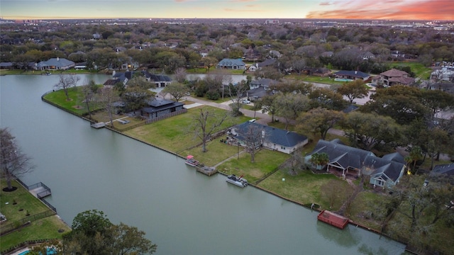 aerial view at dusk featuring a residential view and a water view