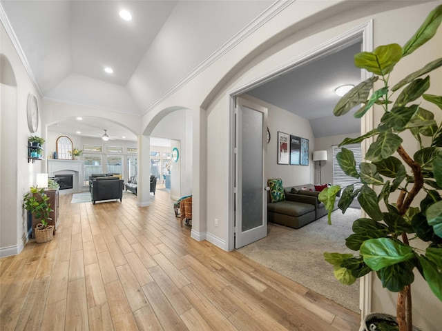 hallway featuring light wood finished floors, baseboards, arched walkways, vaulted ceiling, and recessed lighting