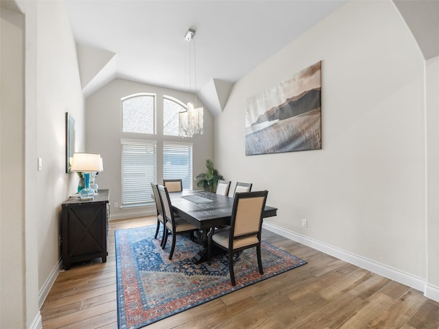 dining room with a notable chandelier, baseboards, vaulted ceiling, and wood finished floors