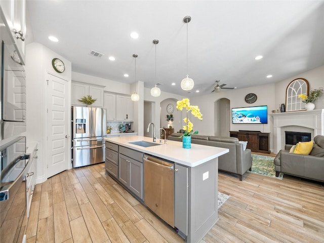 kitchen featuring arched walkways, stainless steel appliances, a sink, visible vents, and gray cabinets