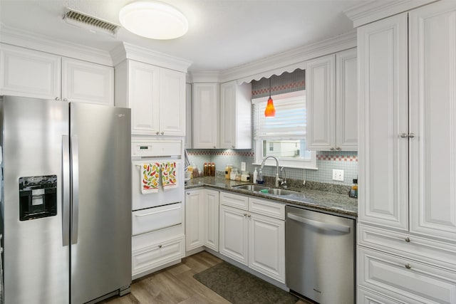 kitchen featuring a warming drawer, visible vents, a sink, wood finished floors, and appliances with stainless steel finishes