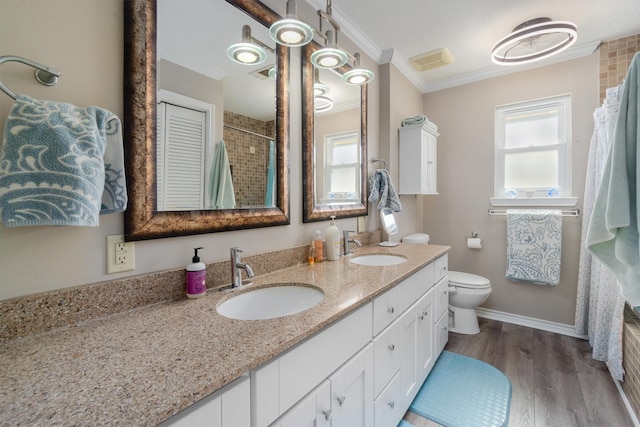 bathroom with a tile shower, wood finished floors, crown molding, and a sink