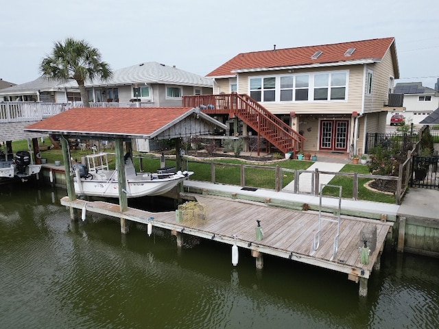 dock area featuring stairway, a fenced backyard, a water view, boat lift, and a lawn