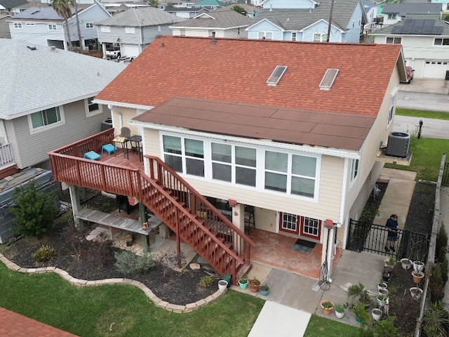 back of house with stairway, a shingled roof, a patio, and a residential view