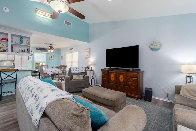 living area with visible vents, ceiling fan, baseboards, lofted ceiling, and wood finished floors