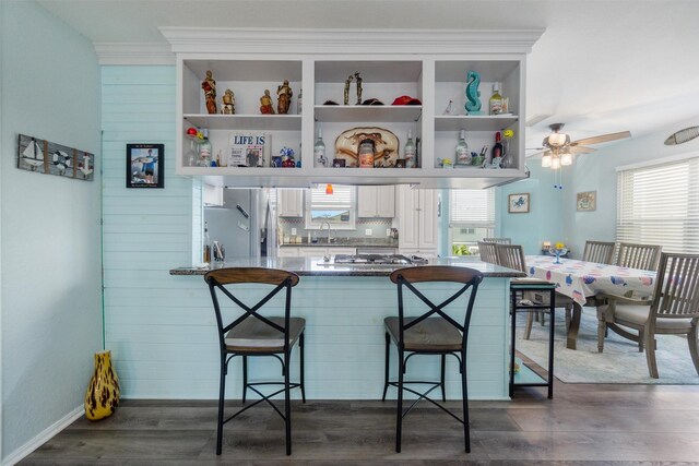 kitchen featuring dark wood-style floors, white cabinets, a breakfast bar area, and stainless steel fridge with ice dispenser