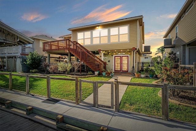 view of front of house with a gate, a fenced front yard, french doors, a front yard, and stairs