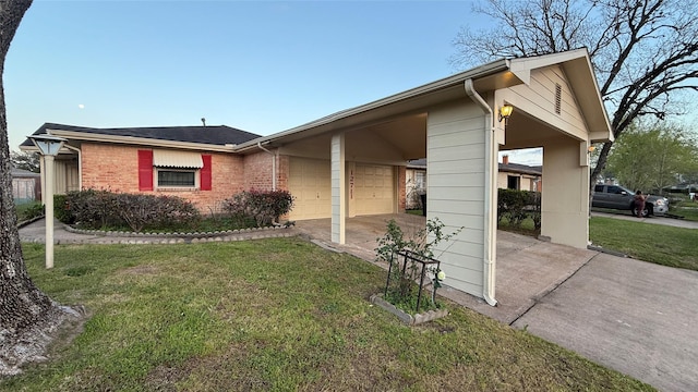 exterior space featuring a yard, driveway, brick siding, and an attached garage