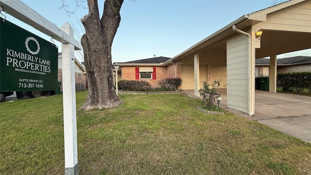 view of side of home featuring a garage, driveway, a lawn, and brick siding