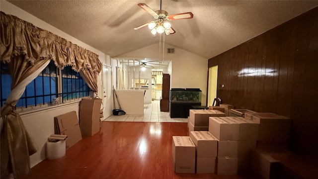 living area featuring visible vents, a ceiling fan, a textured ceiling, wood finished floors, and lofted ceiling