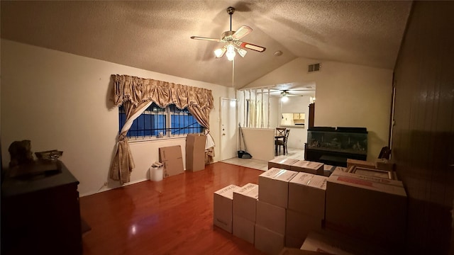 living area with a ceiling fan, wood finished floors, visible vents, lofted ceiling, and a textured ceiling