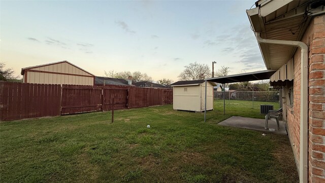 view of yard with central air condition unit, an outbuilding, a patio, a fenced backyard, and a shed