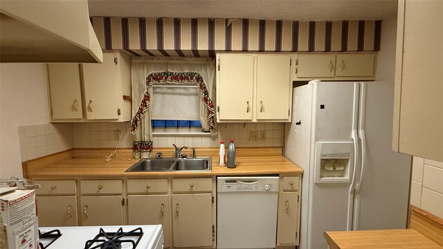 kitchen with tasteful backsplash, white appliances, light countertops, and a sink