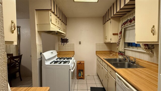 kitchen featuring a sink, white appliances, backsplash, and light tile patterned floors