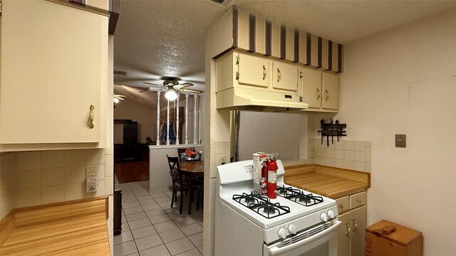 kitchen featuring ceiling fan, under cabinet range hood, white range with gas stovetop, light tile patterned floors, and a textured ceiling