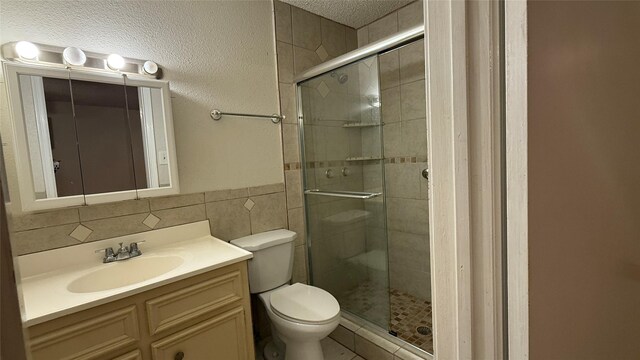 bathroom featuring a shower stall, vanity, tile walls, and toilet