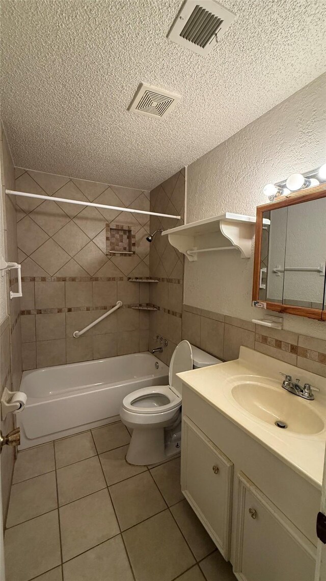 bathroom featuring toilet, a textured wall, visible vents, and a textured ceiling