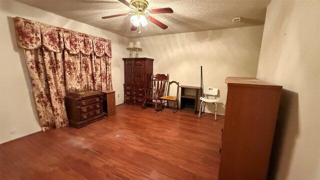 living area featuring a textured ceiling, ceiling fan, and wood finished floors