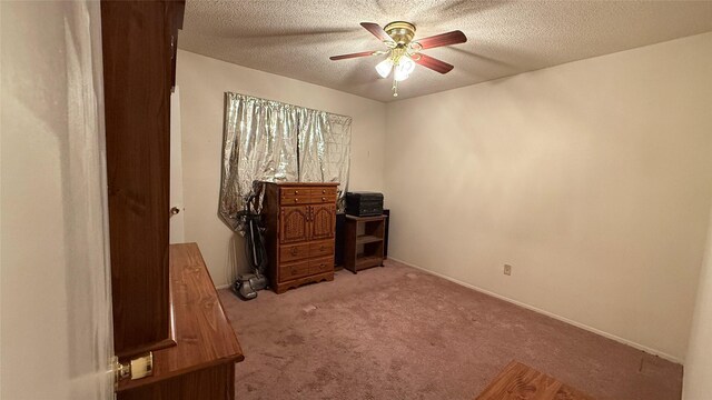 office area featuring a textured ceiling, a ceiling fan, baseboards, and light carpet