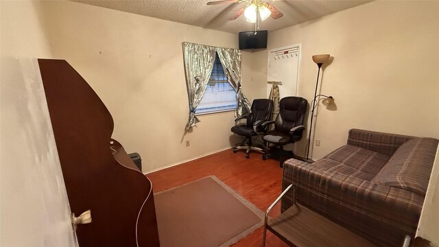 sitting room with a textured ceiling, wood finished floors, baseboards, and ceiling fan