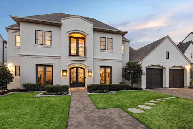 view of front of property featuring french doors, a balcony, a yard, and stucco siding