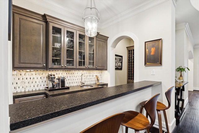 bar with crown molding, indoor wet bar, arched walkways, dark wood-style floors, and a sink