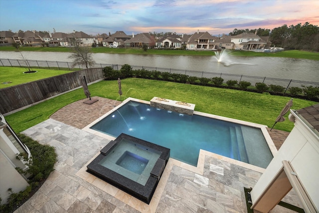 pool at dusk with a residential view, a lawn, a fenced backyard, and a water view