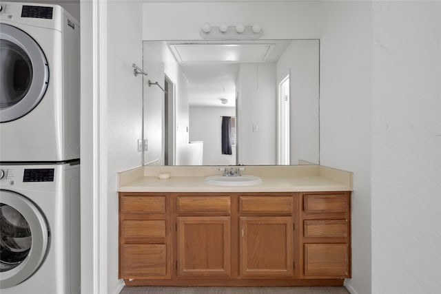 laundry room with a sink, laundry area, attic access, and stacked washer / dryer