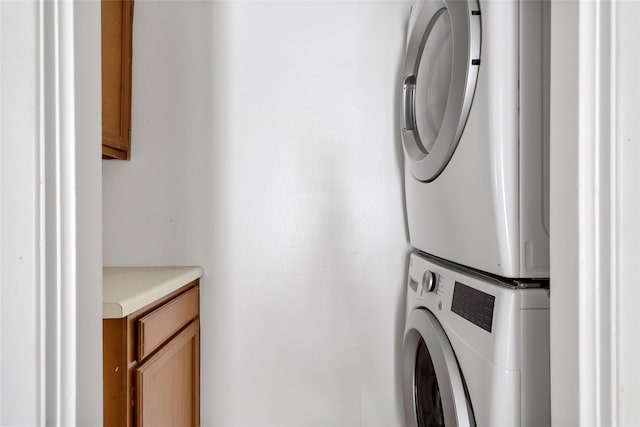 laundry room with cabinet space and stacked washer and clothes dryer