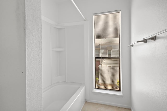 bathroom with tile patterned flooring and washtub / shower combination