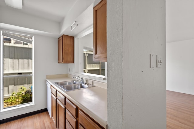 kitchen featuring brown cabinetry, light countertops, a sink, and light wood finished floors