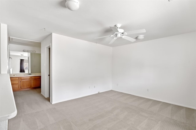 unfurnished bedroom featuring light colored carpet, a sink, ensuite bath, and baseboards