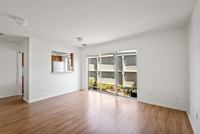 empty room featuring wood finished floors, visible vents, and baseboards