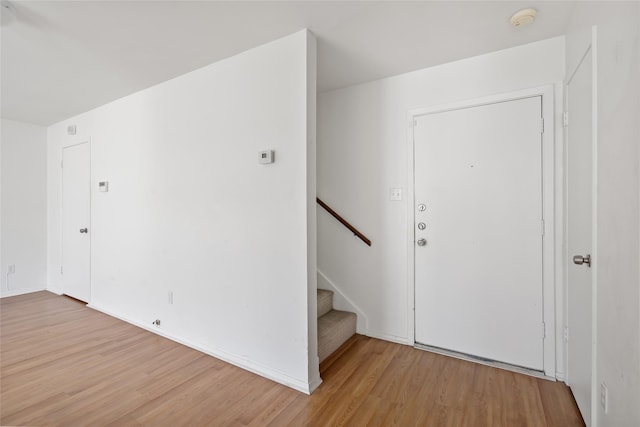 foyer with wood finished floors, baseboards, and stairs